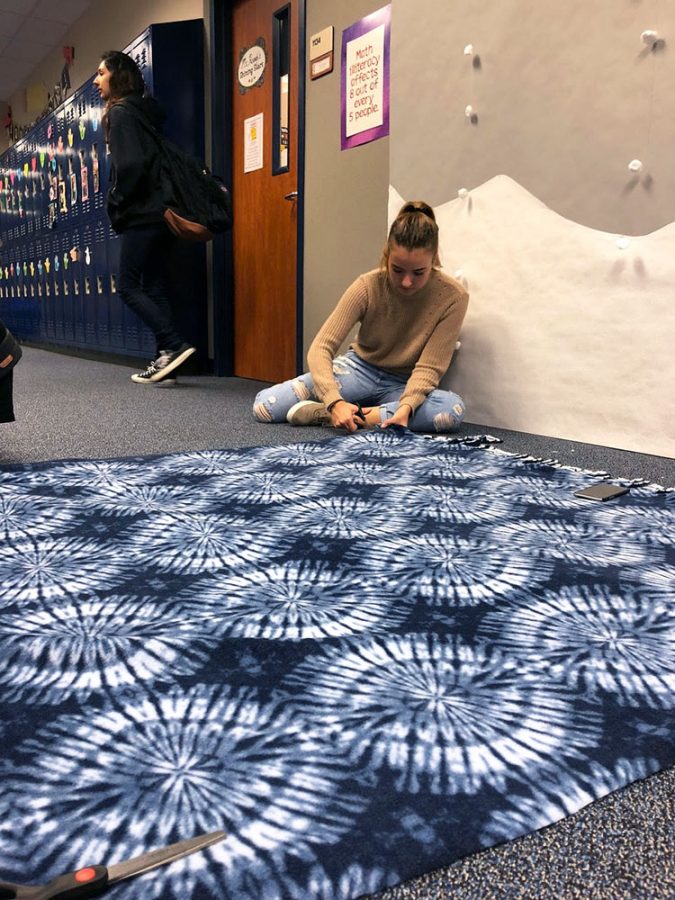 Sofia Rasmussen (12), vice president of Student United Way, makes blankets for the homeless. The blankets will be distributed December 23 to the homeless in Galveston. Additionally, SUW will provide food, pass out jackets and collected toys.