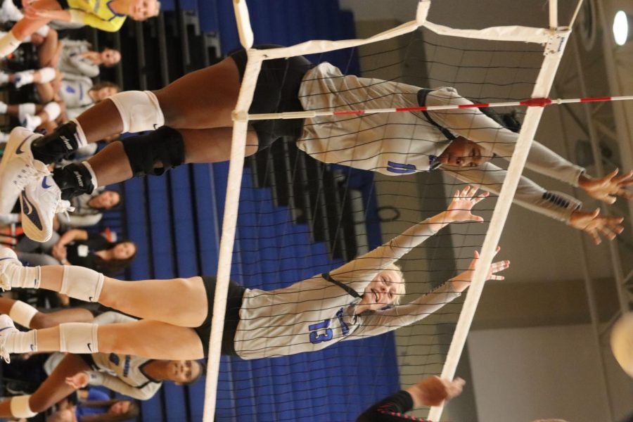 Jumping above the net, Alana Dawson (10) and Erin Rodgers (11) block the ball in the varsity volleyball game against Bellaire.